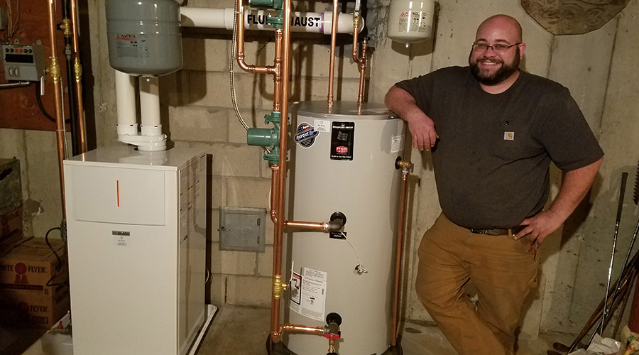 technician posing next to water heater in cellar hyannis ma